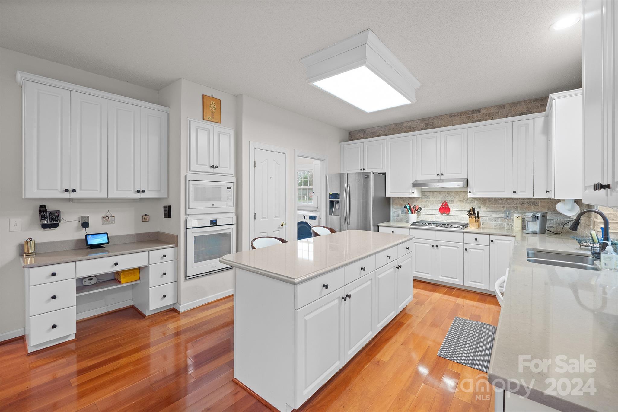 Beautifully designed kitchen at 7681 Orchard Park Cir in Harrisburg, NC, showcasing white cabinetry, a large center island, stainless steel appliances, and ample counter space...