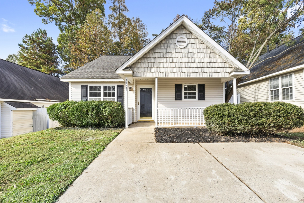 Bright and airy kitchen in a Charlotte, NC home for sale at 3703 Silver Ore Ln, featuring wood cabinetry, white appliances, and a large window for natural light...