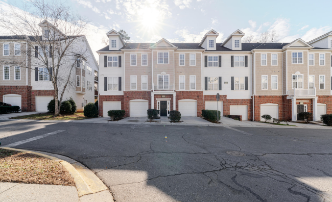 A spacious living area in a Charlotte, NC townhome for sale at 6864 Park Place Dr, featuring an open floor plan, a cozy fireplace, large windows with ample natural light, and access to a private balcony...