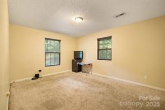 Comfortable secondary bedroom at 1925 Dunavant Street, Charlotte, NC, with soft carpet, warm yellow walls, and two large windows for ample natural light...