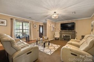 Inviting living room at 1925 Dunavant Street, Charlotte, NC, featuring plush seating, a cozy fireplace, and a mounted TV for a comfortable entertainment space...