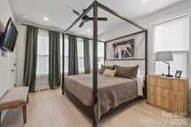 Elegant master bedroom in a Charlotte townhome at 1925 Dunavant St. Features a four-poster bed, stylish decor, ceiling fan, and large windows for natural light...