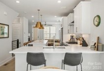 Spacious gourmet kitchen in a Charlotte townhome at 1925 Dunavant St. Features white cabinetry, quartz countertops, gold pendant lights, and a large island with seating...