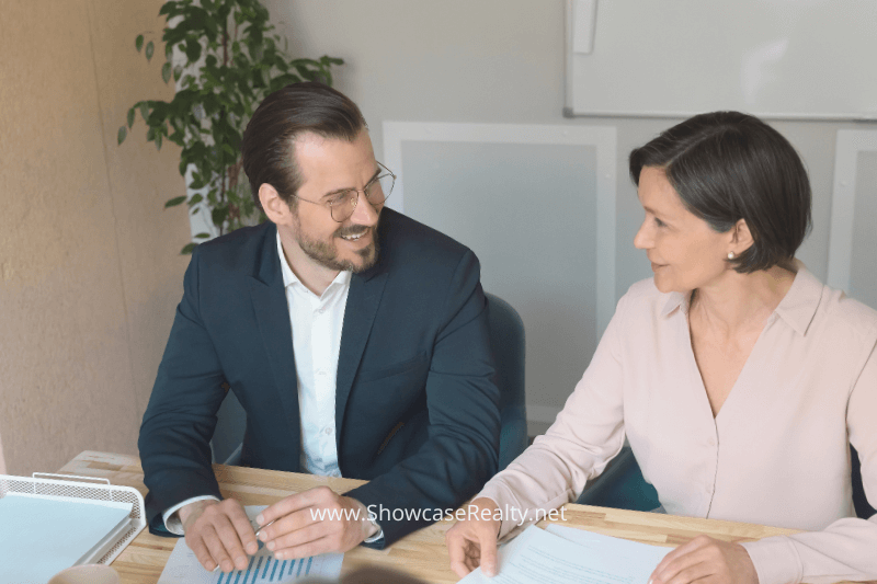 A group of professionals sitting around a table in a meeting, discussing charts and documents related to real estate. This image highlights teamwork and strategic planning for buying or selling Charlotte NC homes for sale, led by top real estate agents like Nancy Braun of Showcase Realty.
