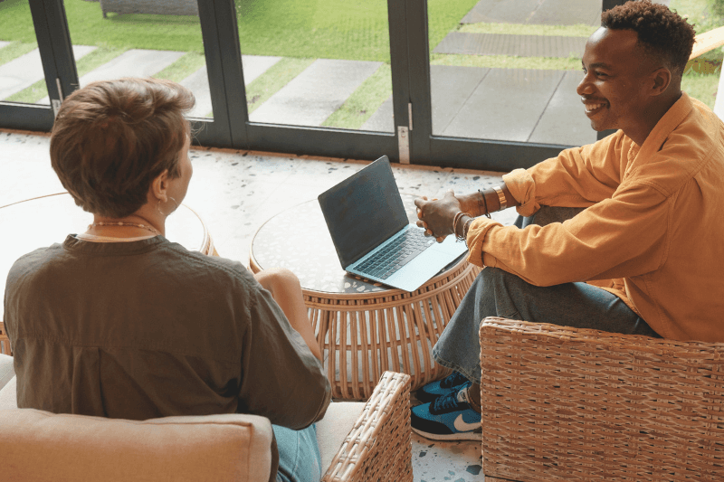  Two people sitting in a modern, bright living space discussing real estate opportunities in Charlotte, NC. A laptop on the table suggests professional planning, highlighting Charlotte NC Investment Properties and the expertise of Nancy Braun at Showcase Realty.
