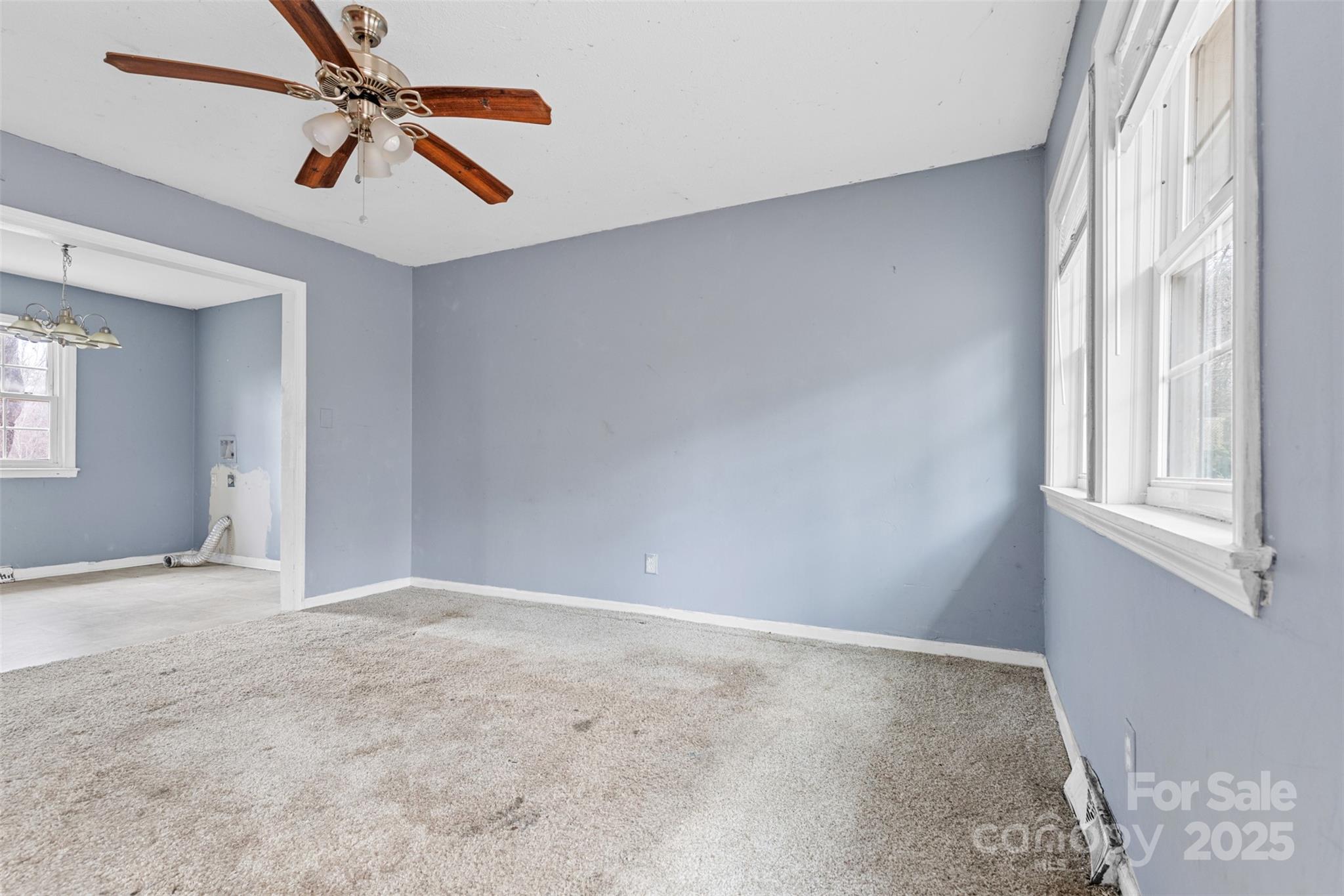 2209 Donnabrook Ln, Gastonia, NC 28052 - 2 A bright living room in a Gastonia, NC home for sale at 2209 Donnabrook Ln, featuring soft blue walls, a ceiling fan, large windows allowing natural light, and an open layout leading to the dining area...