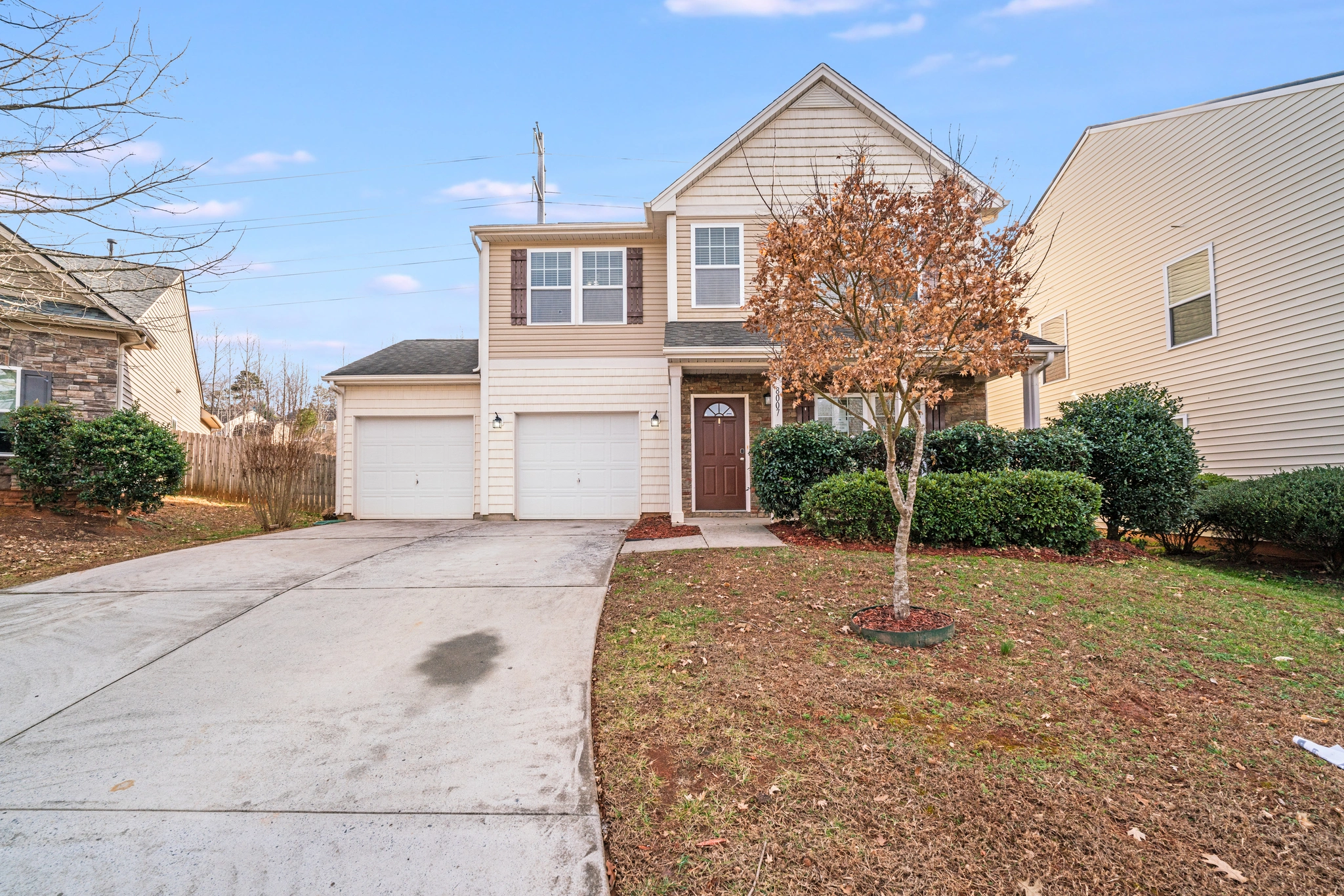 The inviting front exterior of a Charlotte, NC home for sale at 8007 Shadbrush Ct, featuring a two-story design, a covered entryway, a well-maintained front yard with landscaping, and a spacious double garage...