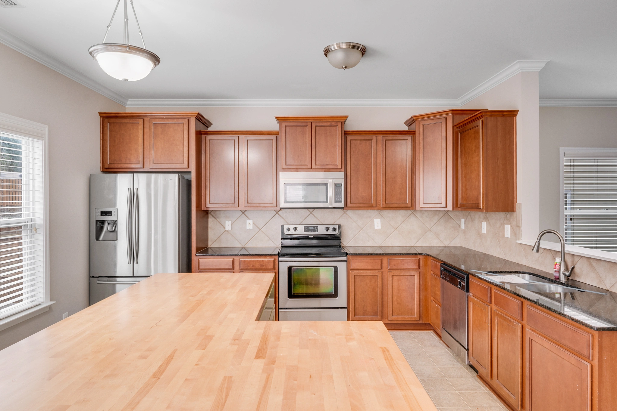 A stunning kitchen in a Charlotte, NC home for sale at 8007 Shadbrush Ct, featuring warm wood cabinetry, stainless steel appliances, a large center island with ample counter space, and natural light from nearby windows...