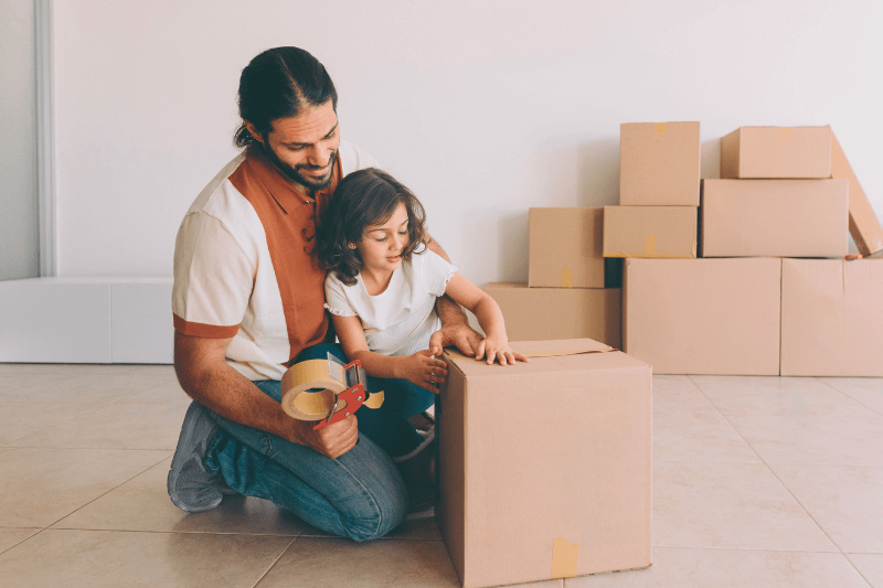 A father and his young daughter pack moving boxes together in a new home, symbolizing the excitement and opportunities of real estate investments. This image highlights the importance of choosing the right financing options for investment properties in Charlotte NC Real Estate with Showcase Realty’s expert guidance.