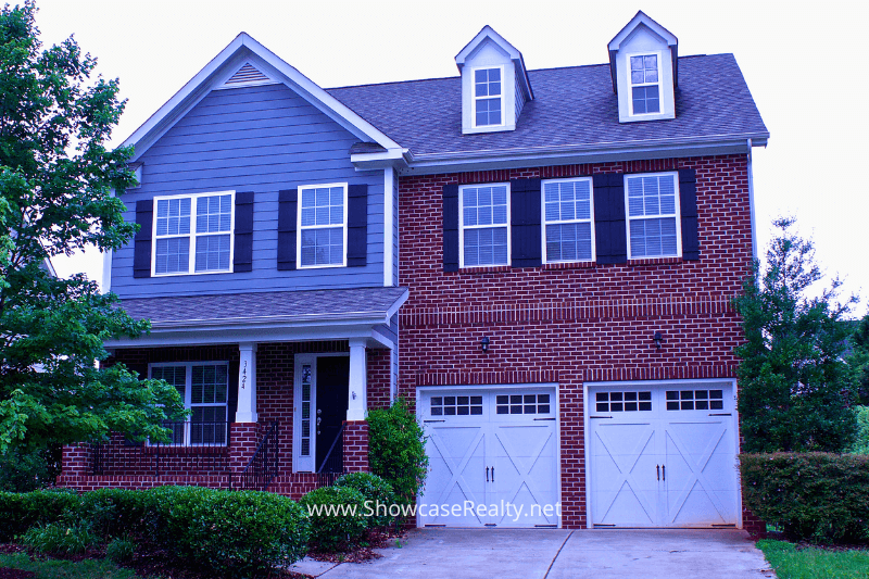 Two-story brick and siding home with a double garage and well-kept landscaping, showcasing a move-in-ready property available through Showcase Realty, highlighting the value and curb appeal found in Charlotte NC real estate and Charlotte NC home buying opportunities.
