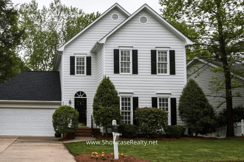 A well-maintained two-story home in a residential neighborhood near Charlotte NC. This home features white siding, black shutters, and lush landscaping—an ideal example of quality properties available through Charlotte NC real estate and Charlotte NC home selling with Showcase Realty.